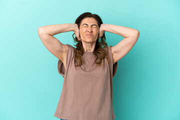 Middle aged caucasian woman isolated on blue background frustrated and covering ears
