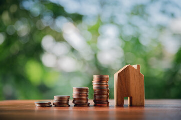 Pile of coins with a wooden house on table financial strategy ideas for real estate investment business.with natural green background.