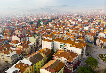 Fototapeta na wymiar Aerial view of Balikesir cityscape with similar brownish tiled roofs on residential buildings in foggy winter day, Turkey.