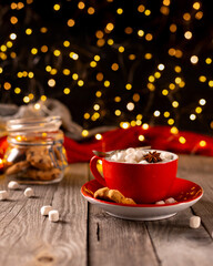 Hot chocolate with marshmallow in red cup on wooden table
