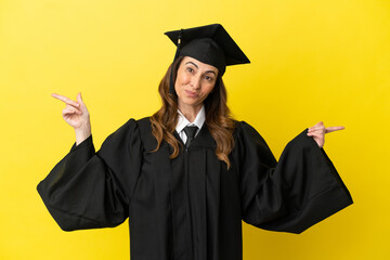 Middle aged university graduate isolated on yellow background pointing finger to the laterals and...