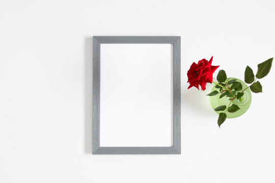 Red rose and photo frame on white background. Flat lay, top view, copy space