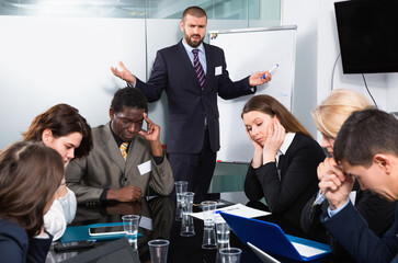 Irritated angry unhappy businessman expressing dissatisfaction with teamwork of colleagues at...