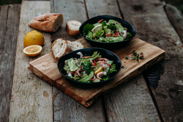 salad with seafood, avocado and herbs on a wooden background