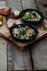 salad with seafood, avocado and herbs on a wooden background