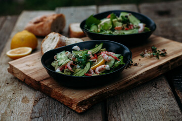 salad with seafood, avocado and herbs on a wooden background