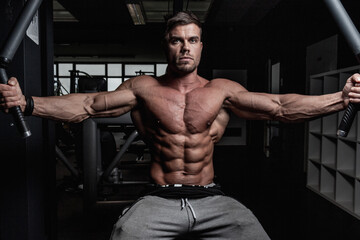 Hard workout of a handsome athletic muscular Austrian man with veins in a dark gym at night