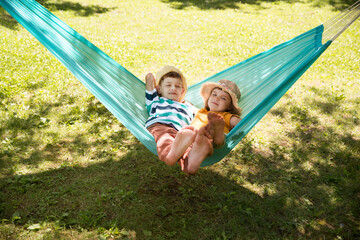 Two kids  swing in a hammock in a summer park or garden.