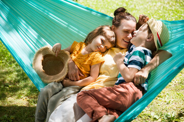 mom and Two kids  swing in a hammock in a summer park or garden. Concept of friendly family.