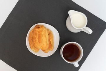 Profiteroles, tea and milk on gray background top view. Puffs, popovers, eclaires.