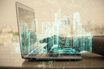 Double exposure of woman hands typing on computer and buildings drawing. Smart-city concept.