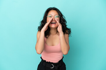 Young asian woman isolated on blue background shouting and announcing something