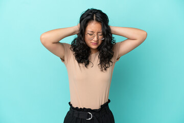 Young asian woman isolated on blue background frustrated and covering ears