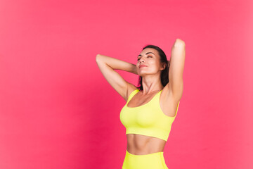 Obraz premium Beautiful fit woman in yellow bright fitting sportswear on pink background happy moving excited perfect body fitness motivation