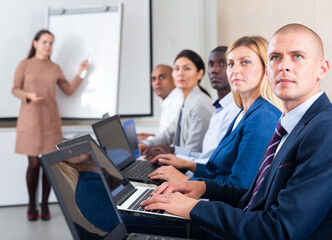 Fototapeta premium Side view of managers group working at laptops in company office