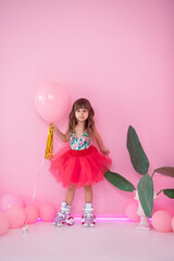 Stylish little girl with rollerblades posing with pastel pink airbaloon on a pink background. Happy...