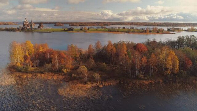 Aerial autimn old Kizhi wooden churches complex on island on lake Karelia authentic traditional rural landscape overall plan. Russia yellow taiga autumn forest. Romantic clouds horizon. Travel movie
