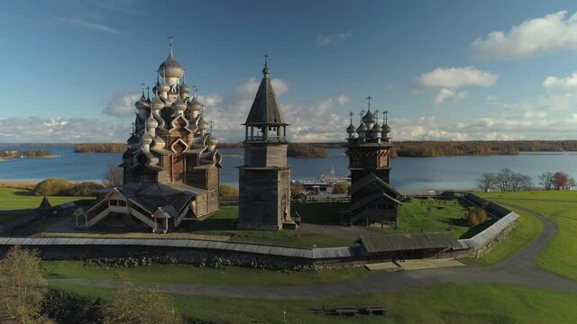 Aerial sideways beautiful historical Kizhi church complex best Russia traditional wooden tample heritage. Unique authentic style landmark on island. Travel cinematic landmark. Sunny, clouds. Stock