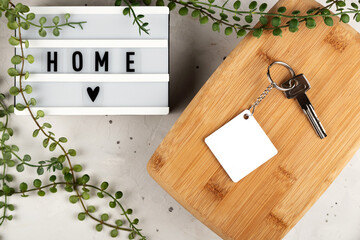 Blank rhombus white sublimation keychain mockup next to board with home inscription. Key chain mockup to display design.