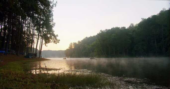beautiful landscape view of nature sunrise in the morning and bamboo raft while floating on the lake and fog mist over water pine forest campsite with camping tent at Pang-Ung, Mae Hong Son, Thailand