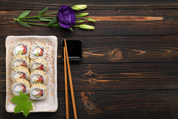 Set of sushi rolls with cream cheese, rice and salmon on a board decorated with ginger on a dark wooden background. Japanese cuisine. Food photo