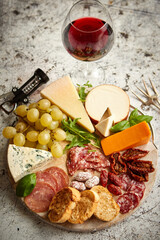 Cold snacks board with meats, grapes, wine, various kinds of cheese