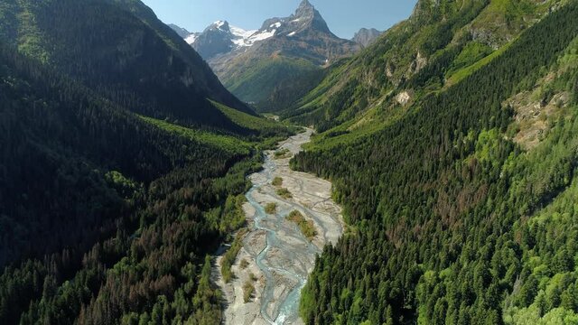 From great height epic Dombay best Russia incredible natural landscape mountains sharp peak, alpine glacial river channels among gorge canyon. Summer sunny green slopes. Travel by helicopter rise