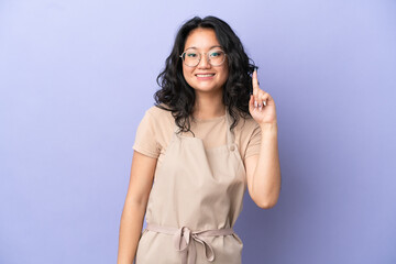 Restaurant asian waiter isolated on purple background showing and lifting a finger in sign of the...
