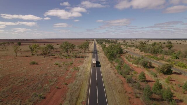 We follow a long haul truck as it makes its way along a highway in the red Australian outback.