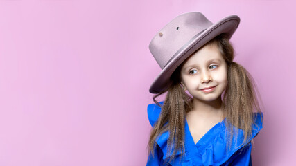 Portrait of beautiful child girl in stylish hat isolated on a pink background.