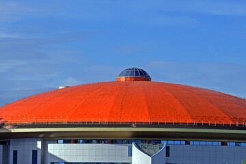 The roof of a sports stadium against a blue sky with white clouds