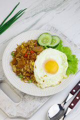 Nasi Goreng or Fried Rice, one of Indonesian popular food, topping with sunny side up egg, cucumber slices, lettuce and crackers. Top view, copy space for text.