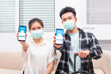 Fototapeta na wymiar Asian young couple woman and man ready to travel showing digital vaccine health passport certificate app in smartphone screen during coronavirus pandemic, Mobile app of virus covid-19 vaccination