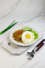 Nasi Goreng or Fried Rice, one of Indonesian popular food, topping with sunny side up egg, cucumber slices, lettuce and crackers. Top view, copy space for text.