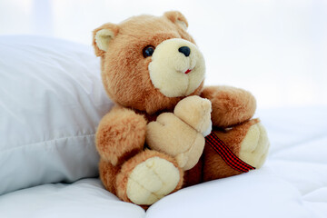 Brown lovely fluffy teddy bear toy sitting alone on bed in bedroom