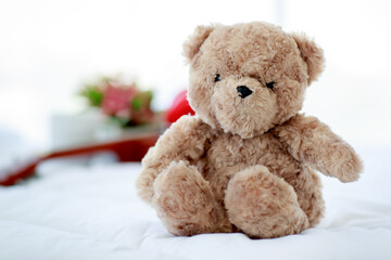 Brown lovely fluffy teddy bear toy sitting on bed near guitar as lovely doll for enjoy music...