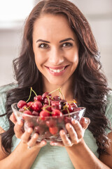 Beautiful woman holding glass bowl full of fres cherries