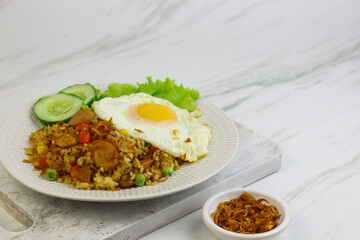 Nasi Goreng or Fried Rice, one of Indonesian popular food, topping with sunny side up egg, cucumber slices, lettuce and crackers. Top view, copy space for text.