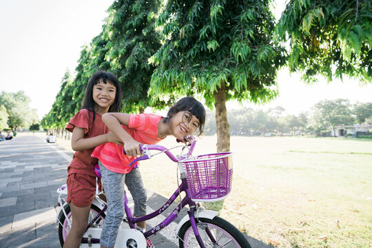 two kids enjoy Ride Bike In the park together. asian kid