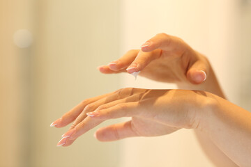 Woman hands applying moisturizer cream in the bathroom