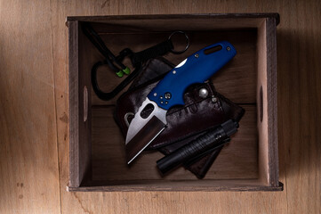 Pocket knife and other everyday items. Wallet and knife in a box. Carabiner and knife. Flat lay. Top view.