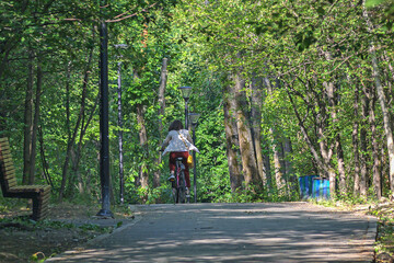 A girl rides a bicycle along a park alley