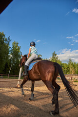 A girl rider on a horse jumps over an obstacle.