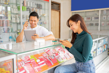 woman using a mobile phone with a male shop assistant in the background sitting in a smartphone shop