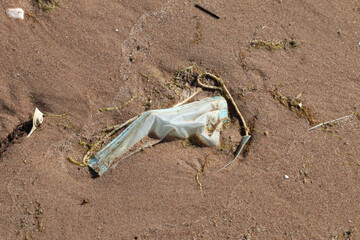 Blue disposable medical mask on the sea sand. medical mask pollution. side effects of the virus