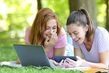 Happy students watching videos on smart phone in a park