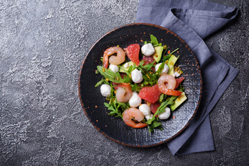 Healthy salad with fresh arugula, mozzarella cheese, tasty shrimps, grapefruit and avocado