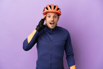 Young Brazilian cyclist man isolated on purple background with surprise and shocked facial expression