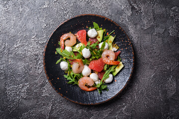 Healthy salad with fresh arugula, mozzarella cheese, tasty shrimps, grapefruit and avocado