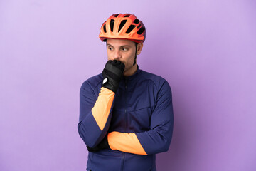 Young Brazilian cyclist man isolated on purple background having doubts - obrazy, fototapety, plakaty